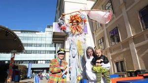 Vier verkleidete Menschen lachen in die Kamera, drei Erwachsene, zwei Kinder, eine erwachsene Person steht auf hohen Stelzen