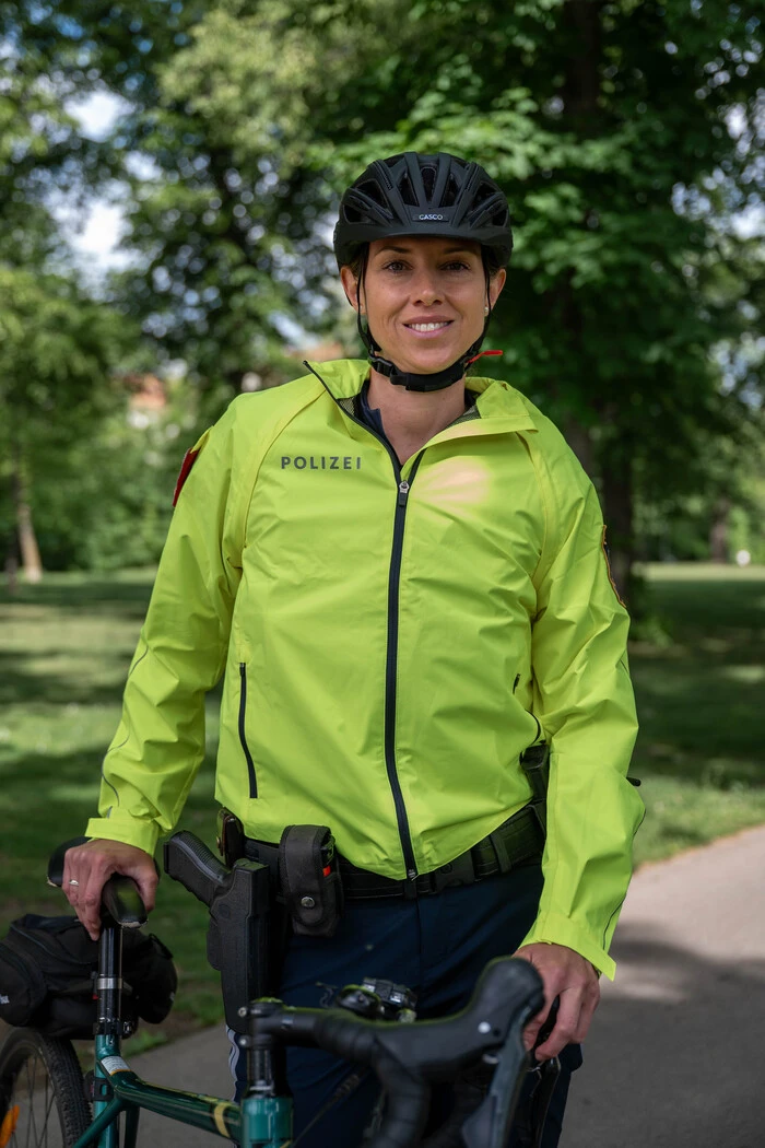 junge Fahrradpolizistin in gelber Jacke
