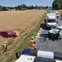 Unfallszenerie: Auto liegt im Acker, zerstörter Pkw steht auf der Straße, Einsatzkräfte bei der Arbeit