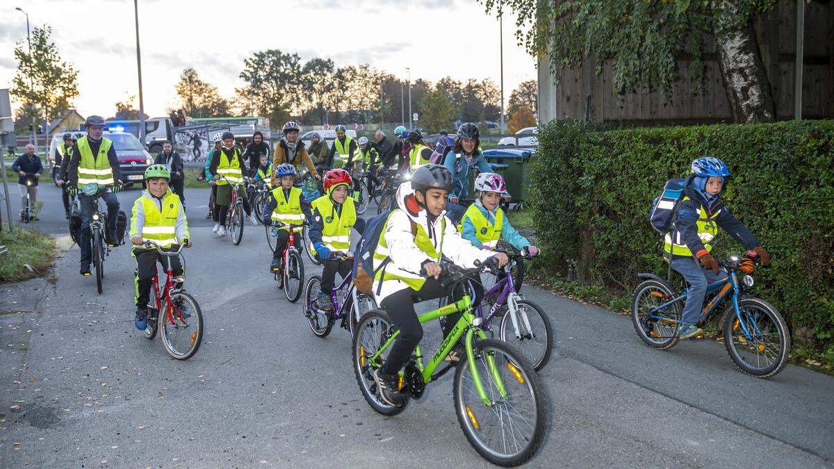 Die Kinder radeln gemeinsam zur Volksschule, begleitet von Eltern und der Polizei