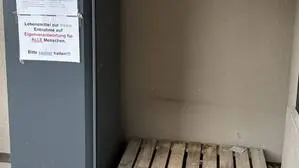 Eine leere Holzpalette, auf der früher der Kühlschrank stand; daneben der noch erhaltene Kasten