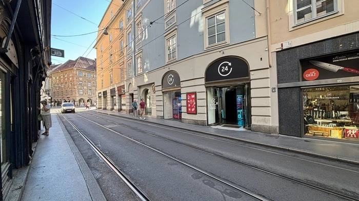 Das Bild zeigt die Murgasse in Richtung Hauptplatz. Die Straße ist leer. Am Gehsteig gehen Menschen.
