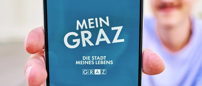 Ein Mann präsentiert die App auf seinem Handy in die Kamera