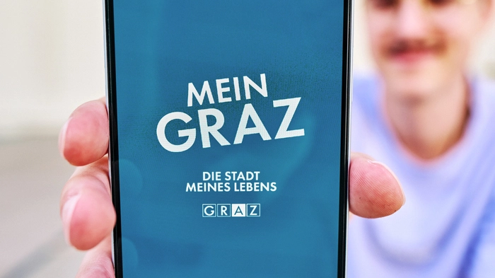 Ein Mann präsentiert die App auf seinem Handy in die Kamera