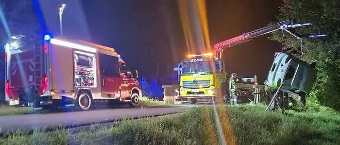 Feuerwehrwagen und ein Abschleppkran, der gerade ein Auto aus dem Bachbett hebt