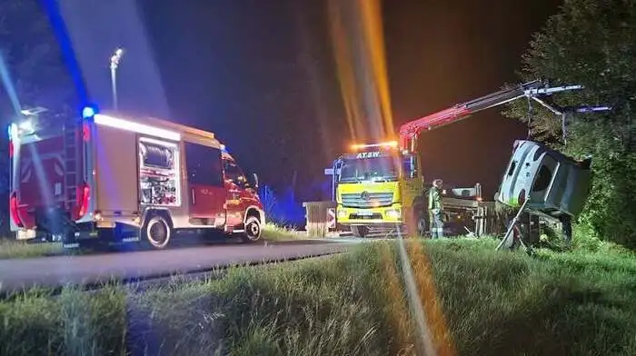Feuerwehrwagen und ein Abschleppkran, der gerade ein Auto aus dem Bachbett hebt