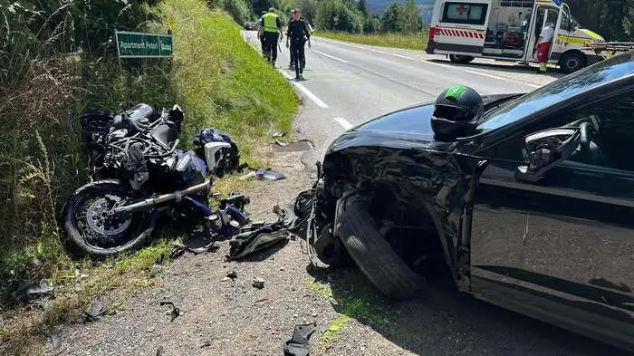 Foto vom Unfallort: Das Motorrad liegt schwer beschädigt am Straßenrand, auch die Front des Pkw ist beschädigt