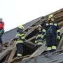 Feuerwehrleute stehen auf einem offenen Dach, das vom Sturm abgedeckt wurde