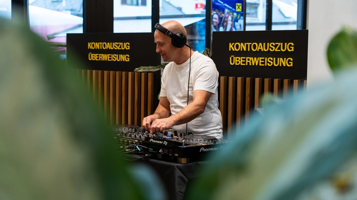 Ein DJ steht in der Bankfiliale und hantiert gerade an den Reglern