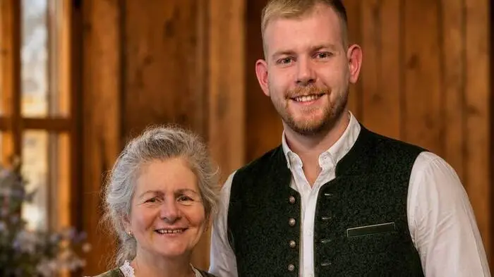 Ein Mann und seine Mutter posieren für ein Foto. Die beiden tragen traditionelle Tracht