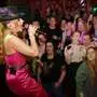 Foto aus dem Lokal: Sängerin Hannah mit Trachtenhut und rosa Kleid singt auf der Bühne, unten stehen die Fans