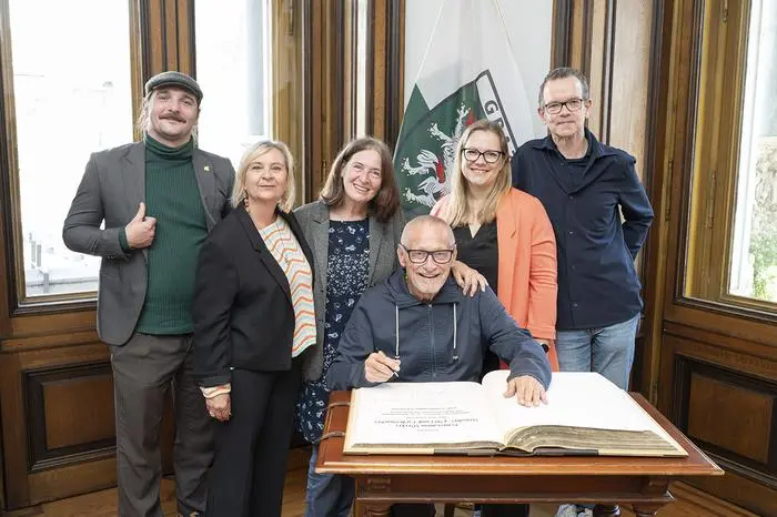 Konstantin Wecker trug sich in das Goldene Buch der Stadt Graz ein. Bild: Bgm.in Elke Kahr (M.), Pianist Jo Barnikel (r.), Claudia Klimt-Weithaler (KPÖ-Abgeordnete zum Steirischen Landtag), SPÖ-Klubvorsitzende Daniela Schüsselberger (2. v. r.) sowie Gemeinderat Tristan Ammerer (l.).