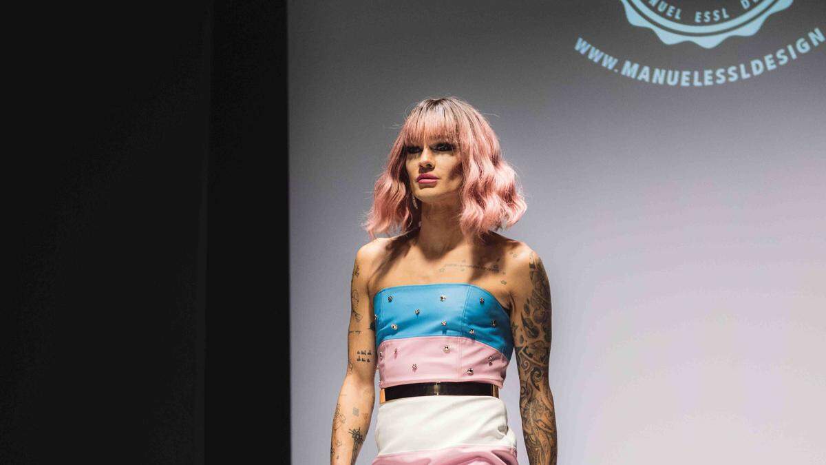 Gloria Hole in einem Kleid in den Farben der Transgender-Flagge von Designer Manuel Essl auf dem Laufsteg bei der Vienna Fashion Week