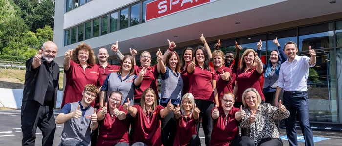 Das Team versammelt sich vor dem Gebäude zu einem Gruppenfoto und bejubelt die Eröffnung