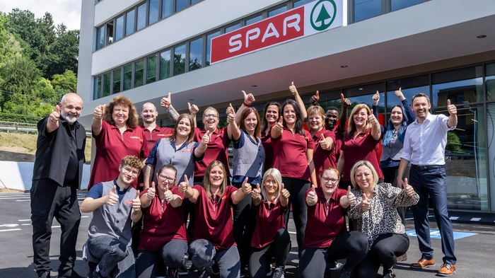 Das Team versammelt sich vor dem Gebäude zu einem Gruppenfoto und bejubelt die Eröffnung