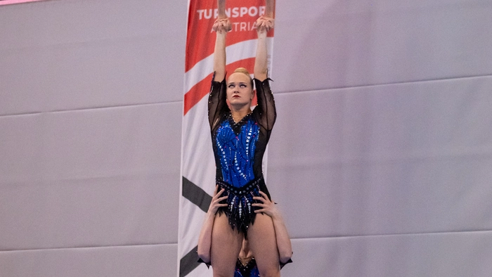 Drei Turnerinnen führen gemeinsam eine Figur in einem Wettbewerb aus.
