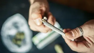 Close up of addict lighting up marijuana joint with lighter. Drug use. Substance abuse