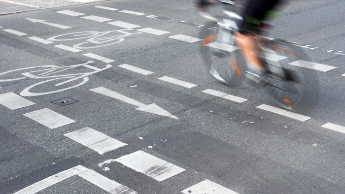 Ein Fahrrad fährt auf einem Radstreifen. Bewegungsunschärfe suggeriert hohe Geschwindigkeit