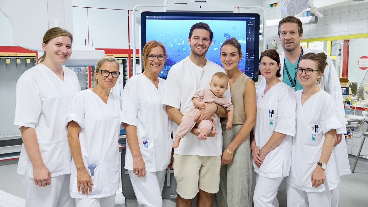 Dr. Gernot Grangl, Leiter des Pädiatrischen Herzkatheter-Labors (zweiter von rechts) mit  Team vor der neuen Angiographieanlage. In der Mitte: die kleine Ilvy mit ihren Eltern  