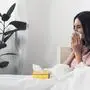 sick young woman with box of paper napkins sitting in bed