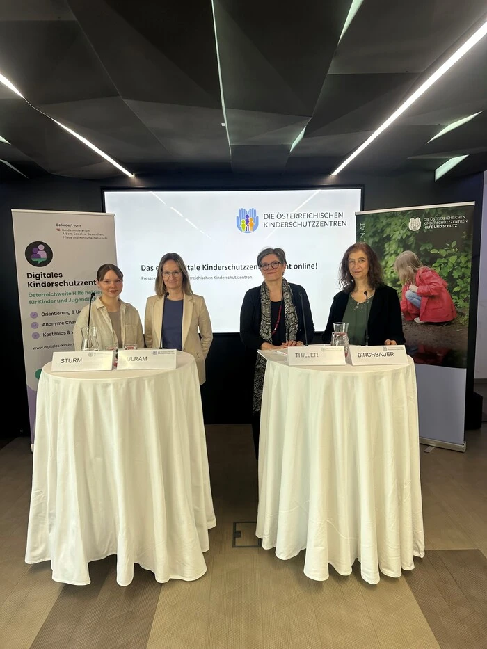 Vier Frauen stehen vor einer Leinwand und hinter zwei Stehtischen mit weißen Tischtüchern