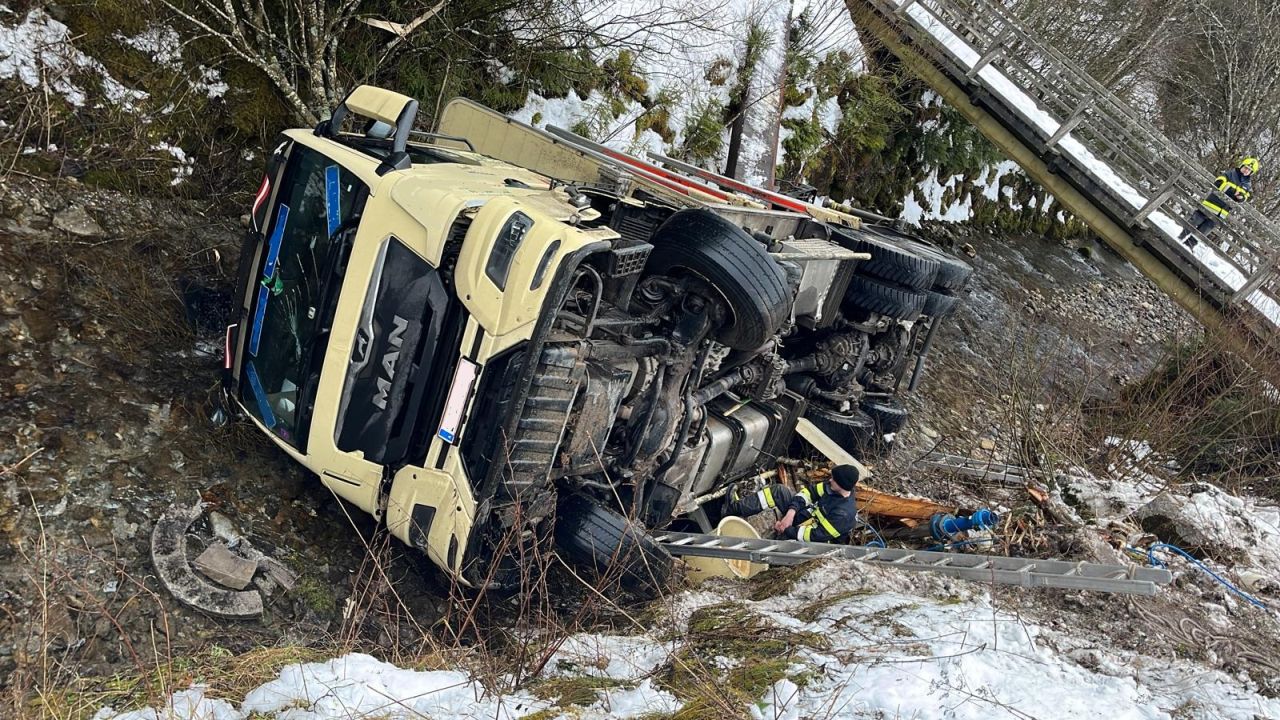 Ein Holztransporter kam von der glatten Straße ab und landete im Bach