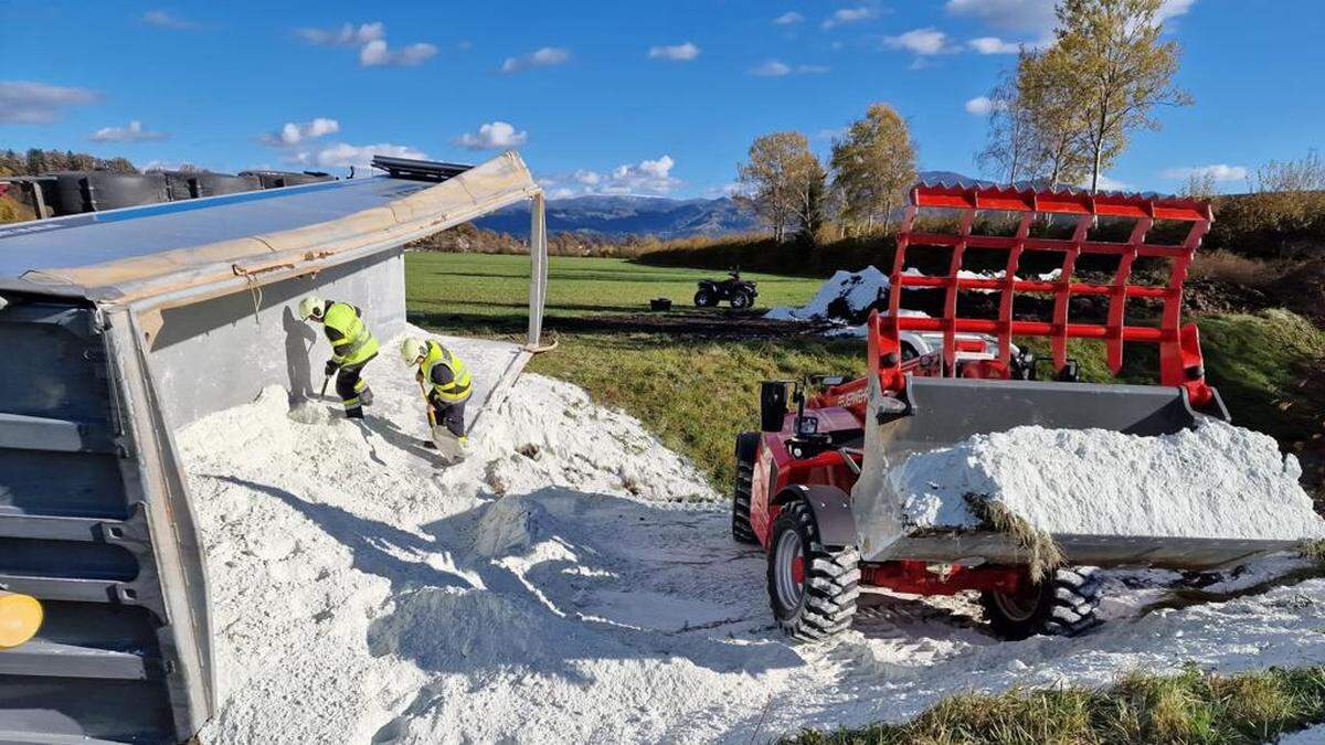 Feuerwehrleute entfernen den Kalk mithilfe eines Teleskopladers und mit Schaufeln