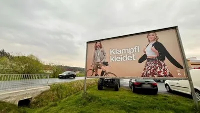 Echte Menschen mit Charisma: Plakat von „Klampfl kleidet“ an der B54 bei Hartl 