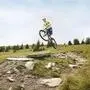 Ein Mountainbiker springt mit seinem Rad über eine Steinplatte auf einem Berghang