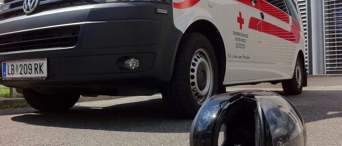 Ein Motorradhelm liegt auf dem Asphalt, dahinter steht ein Rettungswagen