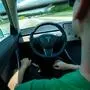 Person driving a Tesla Model 3 in autopilot hands free
