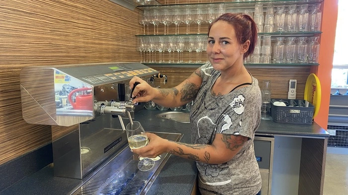 Gastronomin Angelina Witzelnig steht hinter der Theke bei der Schank und befüllt ein Weinglas