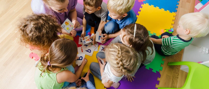 Das Bild zeigt Kindergartenkinder, die in einem Kreis sitzen