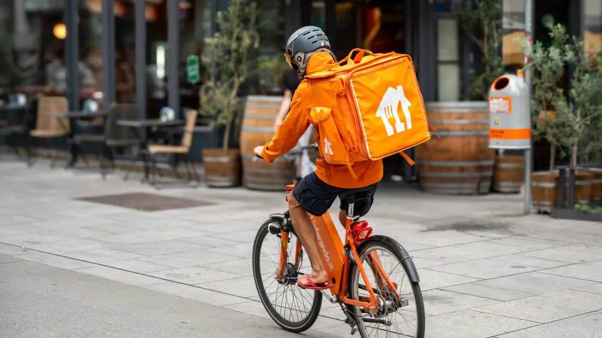 Vienna, Austria, August 23, 2022. A rider from Lieferando, home delivery company for food and drink. It is easy to notice them: the showy orange duffel bag with the typical white logo.