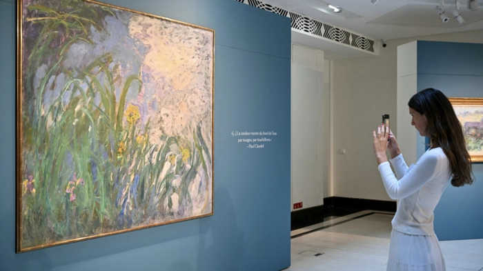 A visitor take a picture of French painter Claude Monet’s painting Iris, 1924–1925, during a preview of 28 Impressionist works from the Schlumberger Collection unveiled ahead of the October 22, 2026, sale at Sotheby’s auction house in Paris on September 17, 2026. (Photo by LOU BENOIST / AFP) / RESTRICTED TO EDITORIAL USE - MANDATORY MENTION OF THE ARTIST UPON PUBLICATION - TO ILLUSTRATE THE EVENT AS SPECIFIED IN THE CAPTION