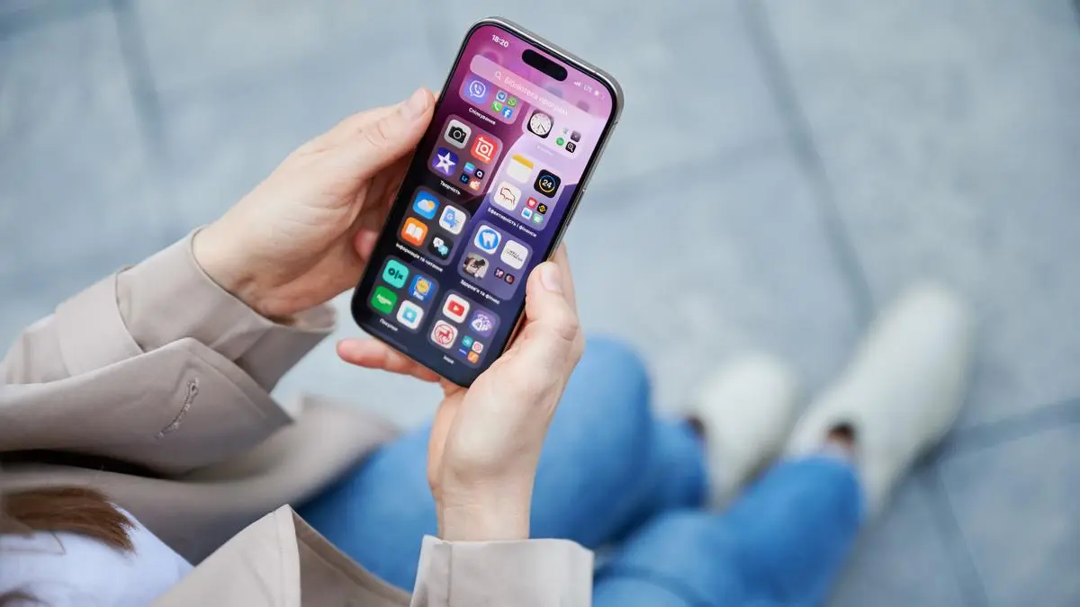 Lviv, Ukraine - October 10, 2024: close up person interacts with smartphone Iphone 16 Pro, navigating home screen filled with apps and widgets, showcasing sleek user interface, personalized features.