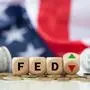 The Federal Reserve ( FED ) to control interest rates. Wooden blocks FED on coins with USA flag background. American economy and business. Federal Reserve Bank Interest rates rise policy. FED concept.