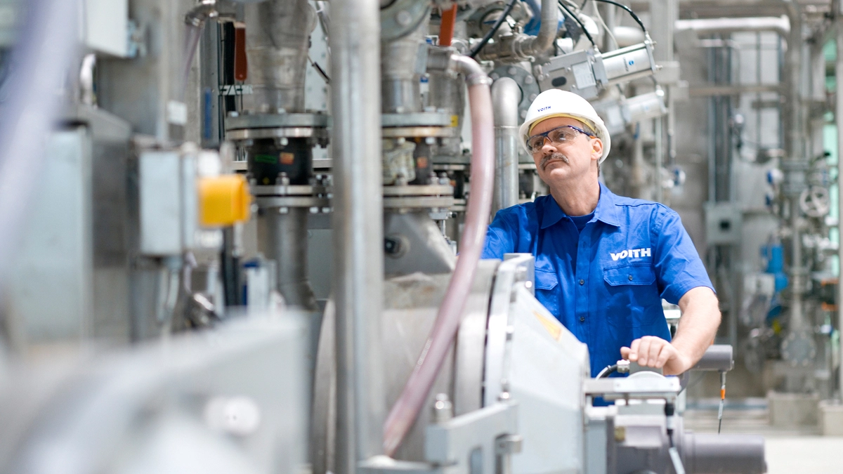 Ein Mitarbeiter des Anlagenbauers Voith arbeitet an einer Papiermaschine | Der Maschinenbauer Voith fertigt auch Papierproduktionsanlagen