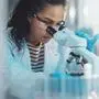 Medical Science Laboratory: Portrait of Beautiful Black Scientist Looking Under Microscope Does Analysis of Test Sample. Ambitious Young Biotechnology Specialist, working with Advanced Equipment